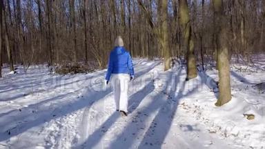 从高处到穿着温<strong>暖</strong>衣服的女人，在美丽的<strong>冬季</strong>白雪覆盖的风景中漫步在一条小径上。 清楚